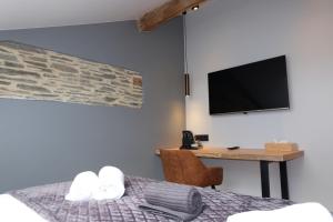 埃尔伯蒙Le Cerf d'Or的一间卧室配有一张床和一张书桌及电视