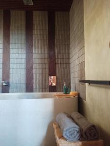 NgaglikBaku living villa的一间带浴缸的浴室,在架子上备有毛巾