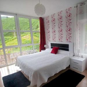 TudancaAlojamiento rural El Refugio的卧室配有白色的床和红色枕头