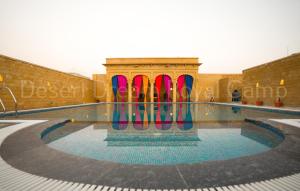 斋沙默尔Desert Dream Royal Camp with Pool的一座建筑物中央的游泳池,上面有色彩缤纷的冲浪板