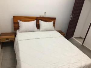 阿比让住宿旅游酒店的卧室配有一张带白色床单和枕头的大床。