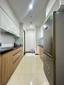 胡志明市Qhome的厨房配有不锈钢冰箱和木制橱柜