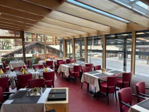 茨韦西门Post Hotel Vista的餐厅设有桌子和红色椅子以及窗户。