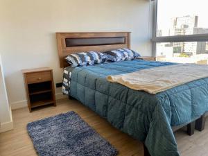 圣地亚哥Departamento ñuñoa的一间卧室配有一张带蓝色棉被的床和窗户。