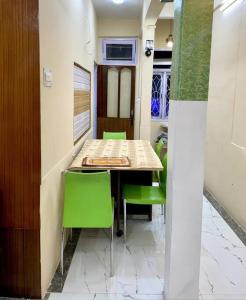 甘托克The First House - 2 BHK in Main Gangtok的一间带桌子和绿色椅子的用餐室