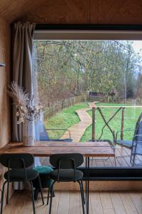 菲利普维尔Ekko tiny house的客房设有桌椅和大窗户。