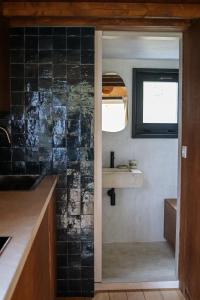 菲利普维尔Ekko tiny house的厨房设有黑色瓷砖墙和水槽
