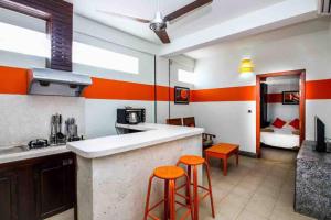 金边CHILCHILL Elite Residences BKK2的厨房拥有橙色和白色的墙壁和橙色的凳子