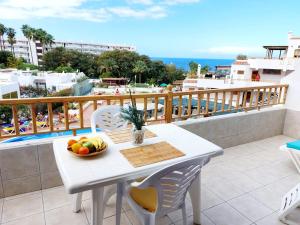 阿德耶FIRST LINE Los Geranios Ocean View Apartment Air Conditioned 50 m from La Pinta beach的阳台上的白色桌子和一碗水果