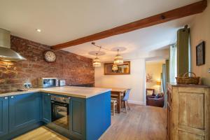 Armathwaite2 Eden Grove Cottages的一间设有蓝色橱柜的厨房和一间用餐室