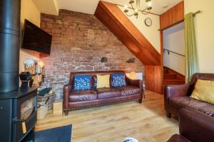 Armathwaite2 Eden Grove Cottages的客厅设有真皮沙发和石墙