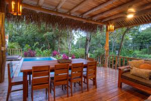 Playa PeladaTreehouse Chilo at Hacienda Nosara的木制甲板配有木桌和椅子