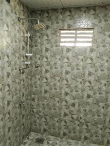达瓦拉维Milk House Cottage的带淋浴的浴室(带石墙)
