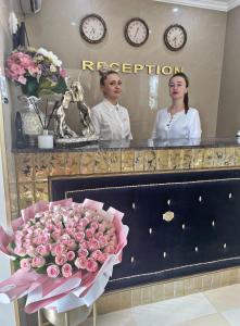 基希讷乌Diamond Hotel的两个女人站在镜子前,花束