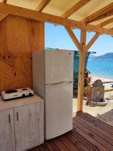 托罗尼Camping Anamour的海滩旁的木地板上摆放着白色冰箱