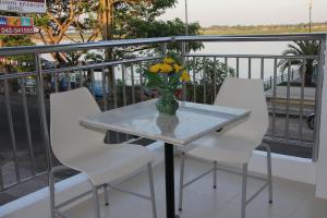 That Phanom那帕侬河景酒店的阳台上配有一张带白色椅子的桌子和花瓶