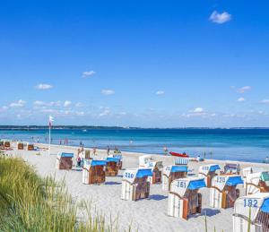 沙博伊茨٤Sweet Spot٤Geräumig-King Bed-Disney+-Parken的海滩上摆放着蓝白椅子,大海上摆放着