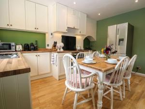 SelborneCharming Country Cottage的厨房配有木桌和白色椅子