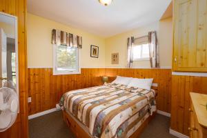 布拉克利海滩Fiddler's Green Country Cottages的一间卧室配有一张带木墙和窗户的床。