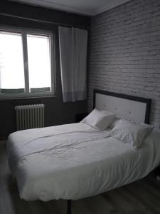 罗德里戈城Alojamiento Roma的卧室内的一张床位,卧室设有砖墙
