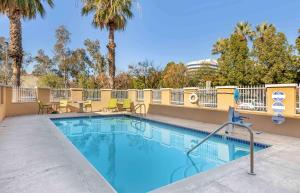 瓜斯蒂美式长居酒店 - 洛杉矶 - 安大略机场的一个带桌椅的游泳池,棕榈树