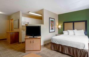 坦帕Extended Stay America Select Suites Tampa Airport Memorial Hwy的配有一张床和一台平面电视的酒店客房