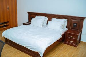 伊巴丹1 Bedroom Bungalow in Alalubosa GRA的一张带木制床头板和白色床单及枕头的床