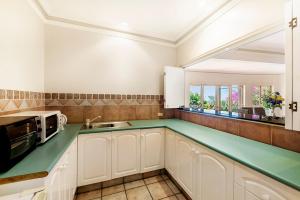 OrmeauTranquil Garden Hideaway的厨房配有白色橱柜和绿色台面