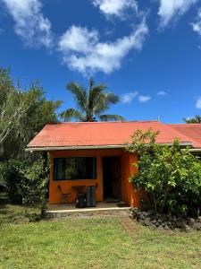 安加罗阿Cabañas Tangaroa y Hamea的一座拥有橙色屋顶和棕榈树的小房子