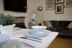 伦敦Deluxe 2 bedroom home in London的一张桌子,上面放有盘子和碗,还有一杯葡萄酒