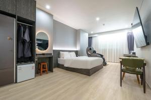 光州H-Evian Hotel的一间卧室配有一张床、一张桌子和一把椅子