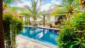帕洋安Dong Loka Guesthouse Bali的棕榈树屋前的游泳池