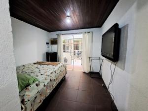 佩德拉德瓜德拉巴Lindo Flat2 a 300 mts da praia posto 12 Recreio的一间卧室配有一张床和一台平面电视
