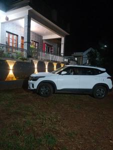 奇克马格尔Chikmagalur cool stay的夜间停在房子前面的白色汽车