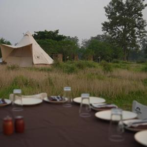 BhurkīāBurhan Wilderness Camps的一张带盘子和玻璃杯的桌子和一个帐篷