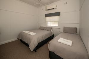 加尔贡The Centennial Hotel Gulgong的配有2张床的小卧室设有窗户