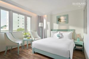 胡志明市Silverland Sil Hotel的卧室配有一张床和一张桌子及椅子