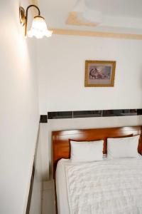 胡志明市THANH NGỌC HOTEL的卧室配有白色的床和木制床头板