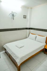 胡志明市THANH NGỌC HOTEL的一张铺有白色床单的床和墙上的灯