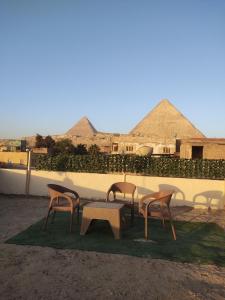 开罗ElBayt motel的一组椅子和一张桌子,后面有金字塔