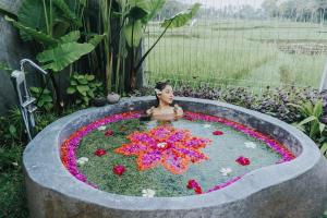 乌布Tri Dewi Residence by Pramana Villas的花园花池中的女人