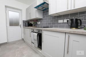 利物浦Newly Renovated 3 Bedroom House with Parking by Amazing Spaces Relocations Ltd的厨房配有白色橱柜和炉灶烤箱。