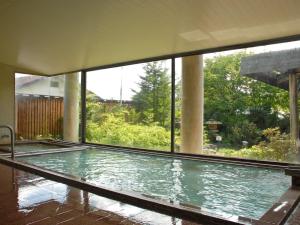 草津草津温泉度假酒店的一座带大窗户的建筑中的游泳池