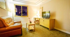 泗川Sacheon Tourist Hotel的一间配备有沙发及电视的酒店客房