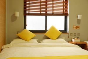 大理大理不羡山精品民宿的一间卧室配有一张带黄色枕头的床和一扇窗户