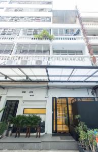 曼谷Theme Stories - Boutique Guesthouse的一座白色的建筑,前面有窗户和植物