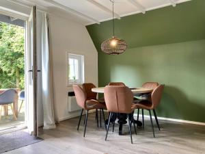 安于姆Olivia 6pers House with a private garden close to the National Park Lauwersmeer的一间拥有绿色墙壁和桌椅的用餐室