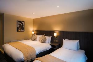 EcclestonPark Hall Hotel,Chorley,Preston的酒店客房设有两张床和两盏灯。