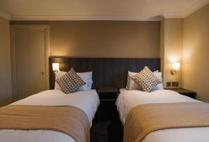 EcclestonPark Hall Hotel,Chorley,Preston的酒店客房设有两张床和两盏灯。