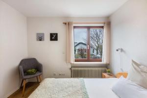 莱茵河畔威尔Ferienwohnung Schwarzwaldblick的一间卧室设有一张床、一个窗口和一把椅子
